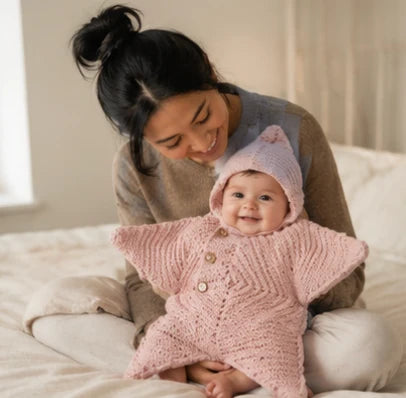 A parent leaning over a baby wrapped in a pink StarSnuggy